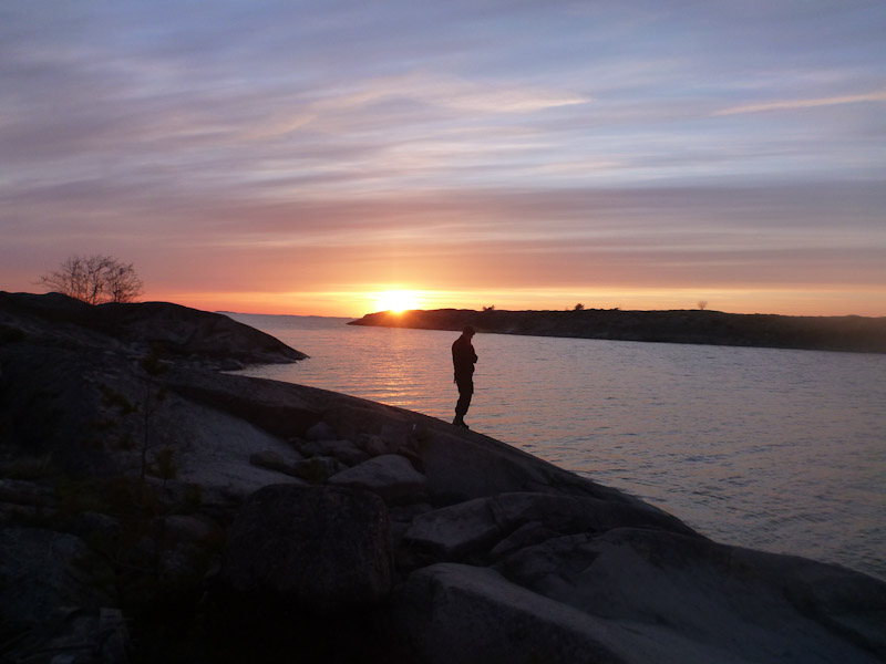 Auringonlasku saarella ja miehen siluetti.
