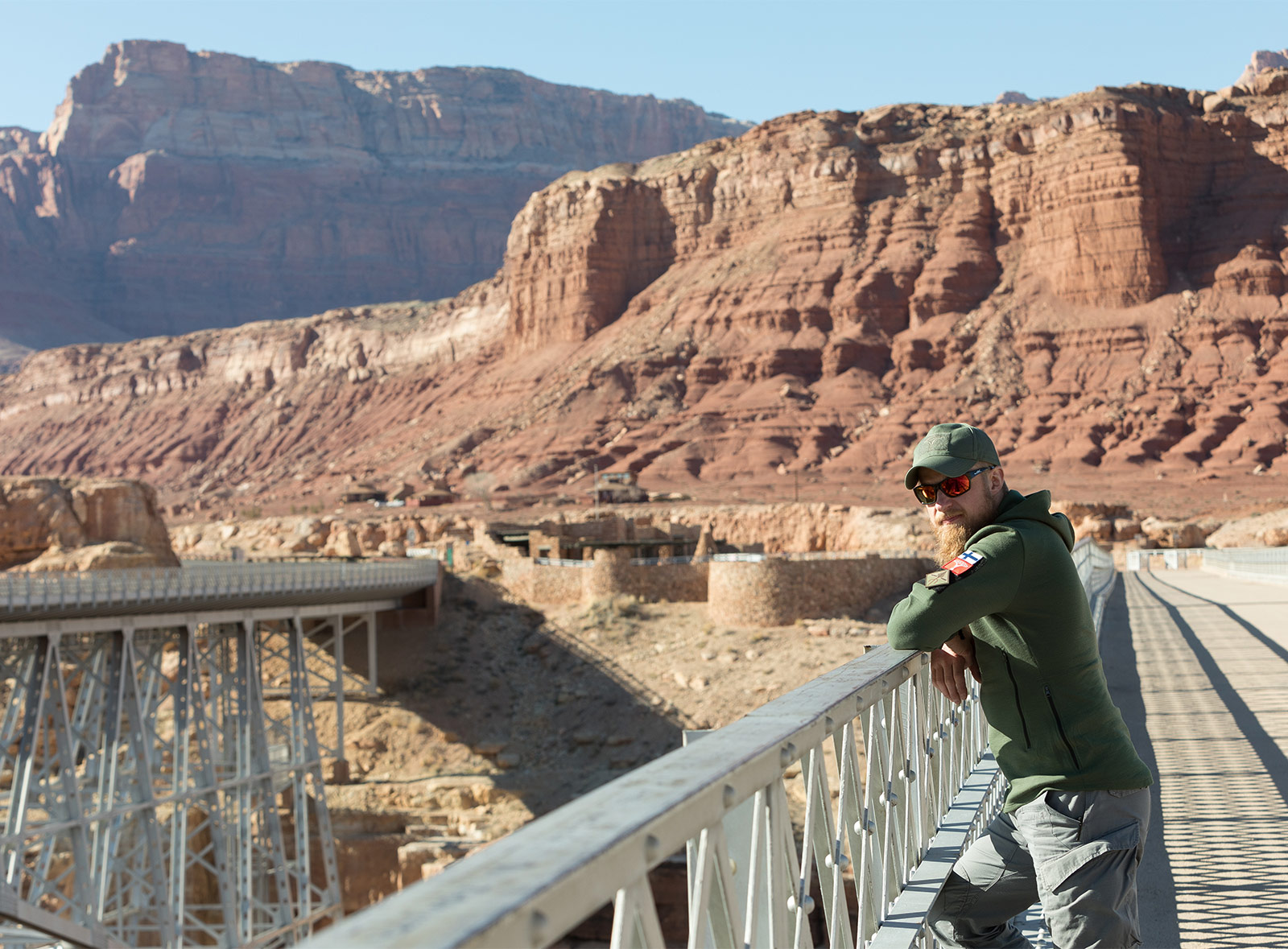 Mies seisoo sillalla punaruskeiden kallioiden ympäröimänä.