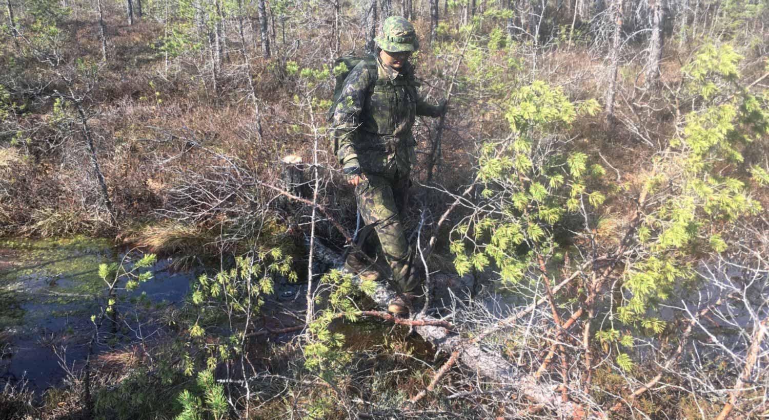 Sotilas ylittää puroa käyttäen puunrunkoa