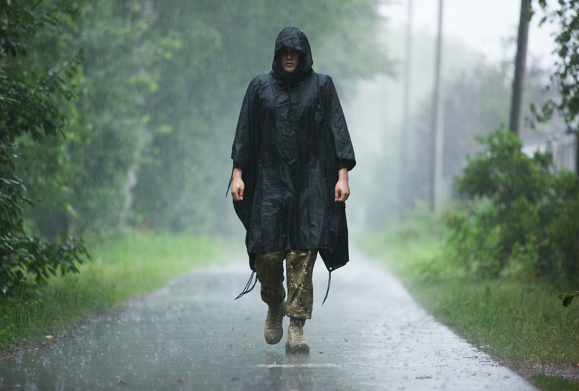 Person walking in the rain with a Särmä rain poncho.