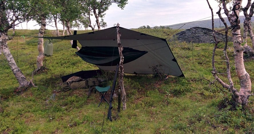 A tarp setup that protects a hammock from wind and rain