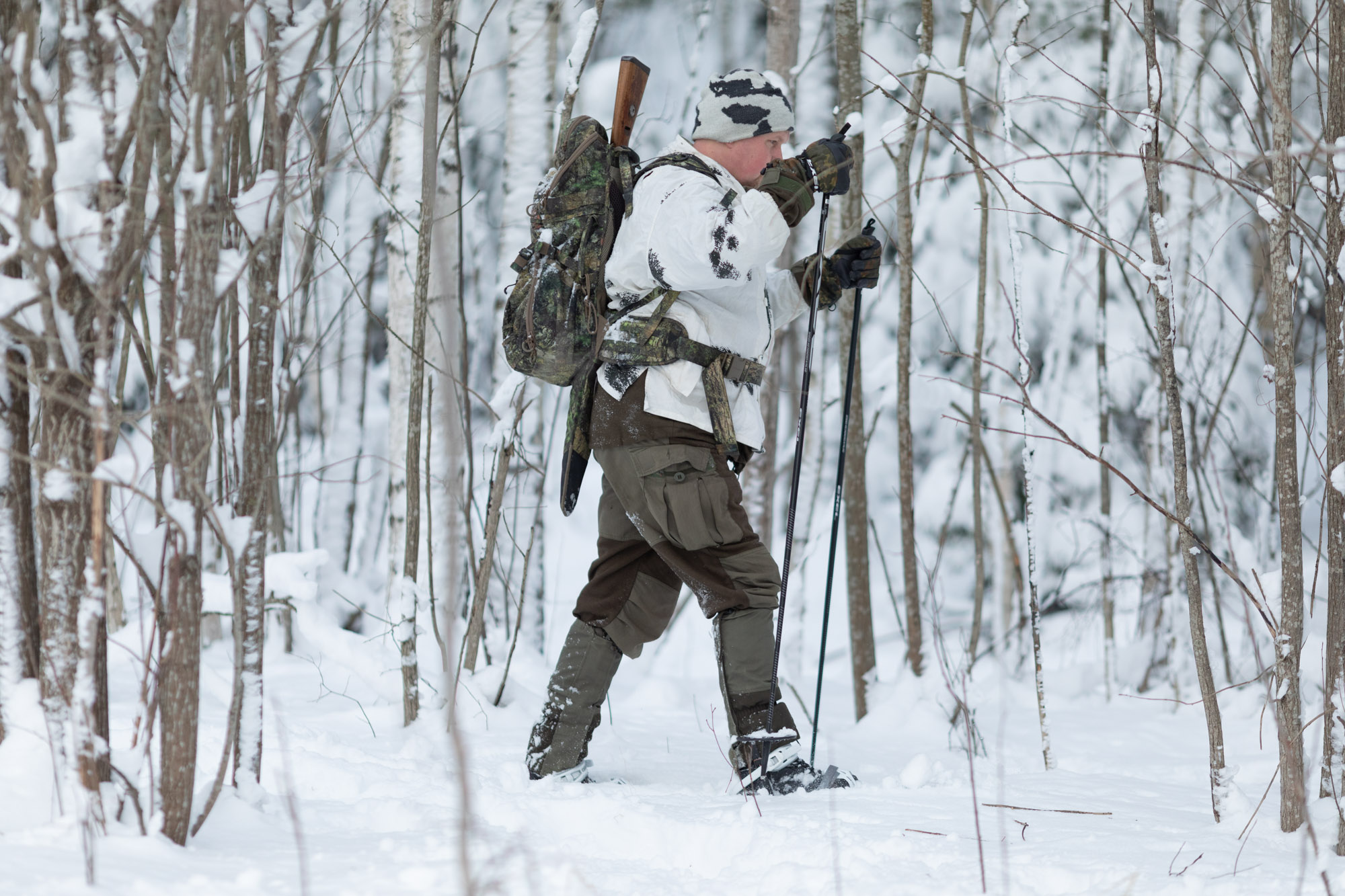 Man skiing in the forest with a rifle pack wearing Salomon Toundra Forces boots