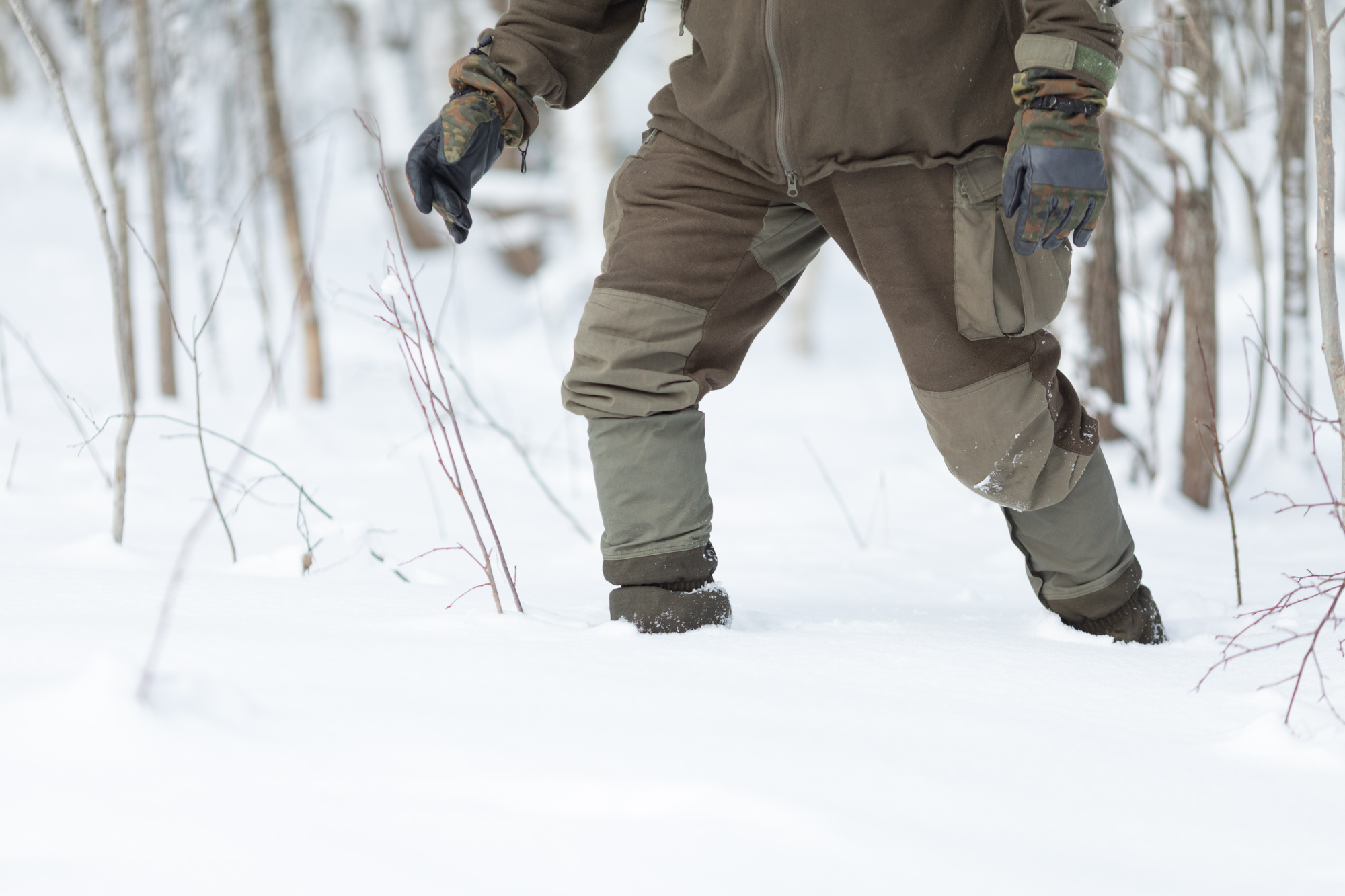 Mies kävelee lumihangessa jalassaan Särmä Woolshell -housut, Gore-Tex-säärystimet ja Salomon Toundra Forces -kengät