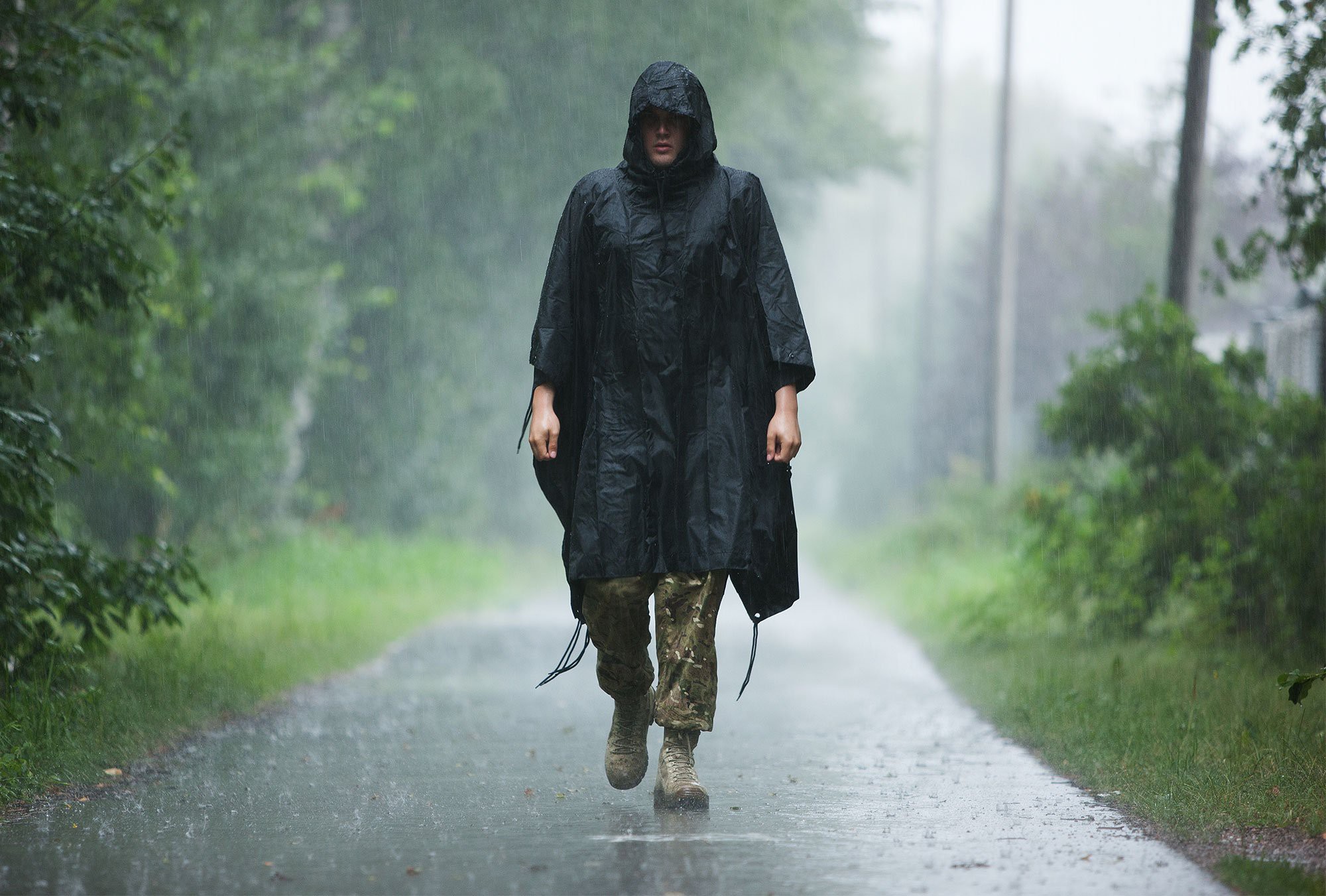 Henkilö kävelee sateessa päällään Särmä sadeviitta.