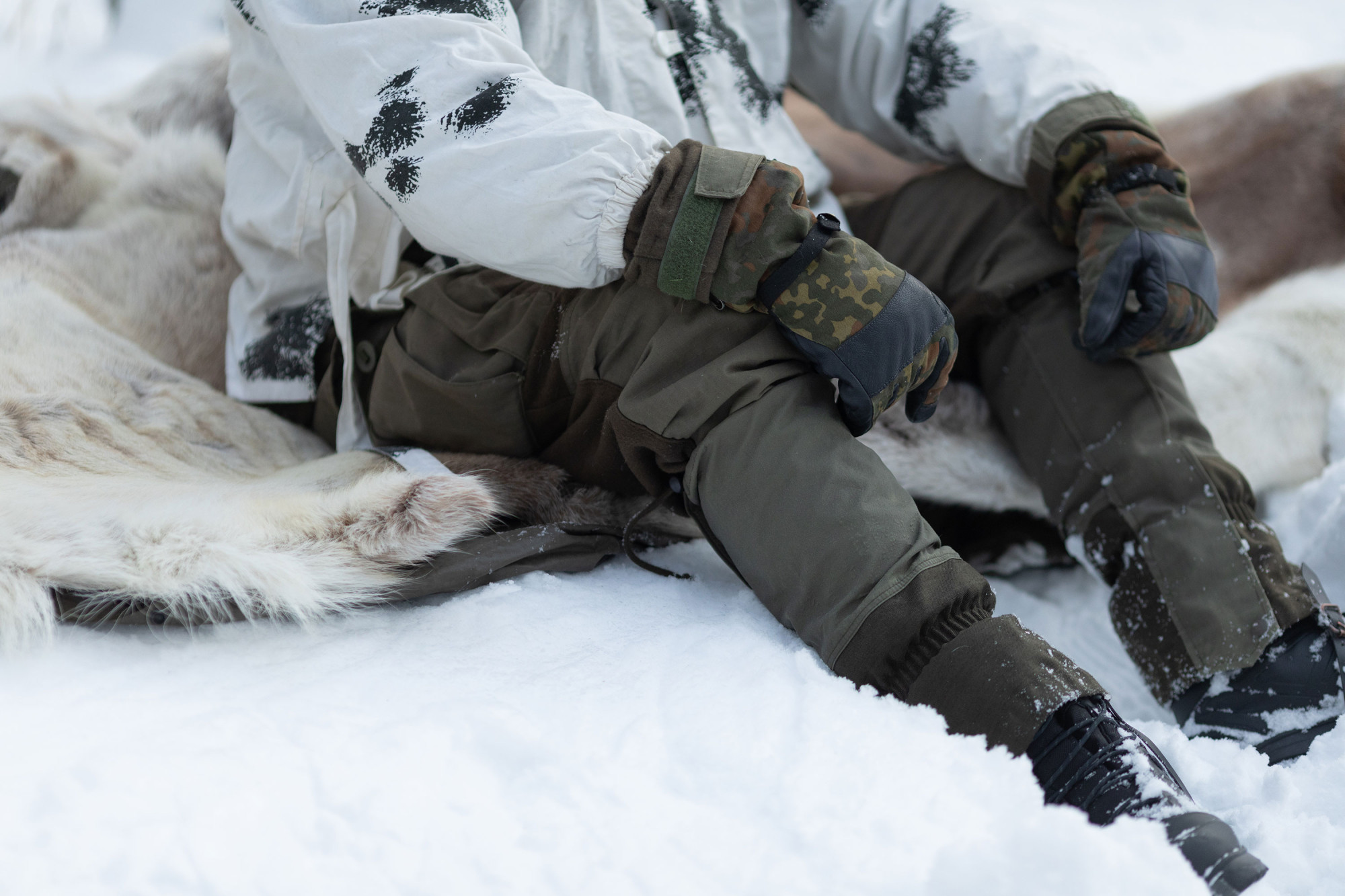 Talviretkeilijä istuu porontaljan päällä lumihangessa